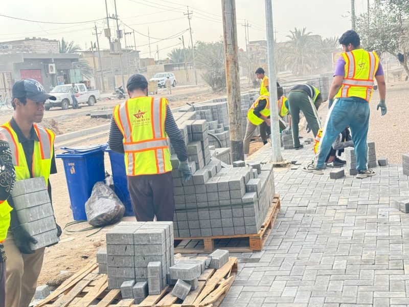 Pallet-fed interlock block laying and progressive sidewalk coverage.