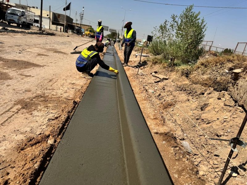 Finishing the freshly poured curb and gutter to alignment strings.