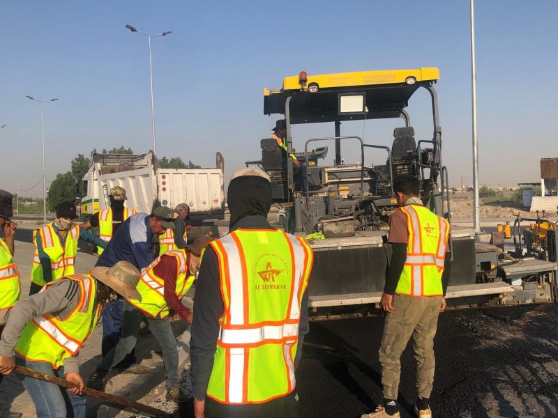 Paver, screed crew and feeder truck on the asphalt wearing course.