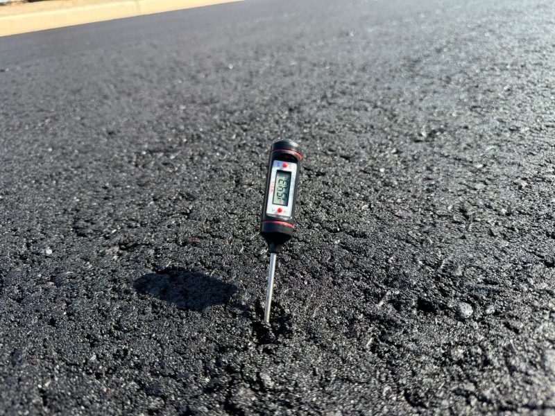 Quality control: laydown temperature check on the freshly laid asphalt mat.
