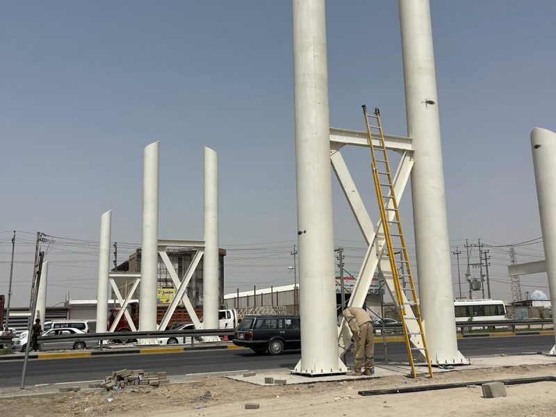 Twin-column steel bridge piers erected on the highway median, ready to receive the deck span.