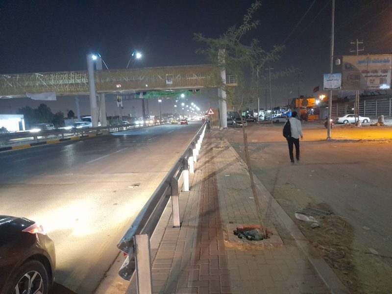 Completed footbridge with street lighting, guardrail and pedestrian sidewalk in night-time operation.
